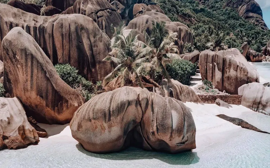 Aerial view of granite boulders, white sand and a clear kayak in the shallows
