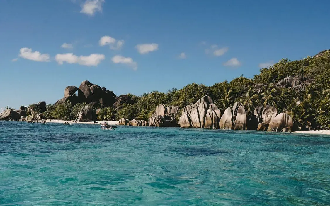 View forward over the bow of a transparent kayak across clear water