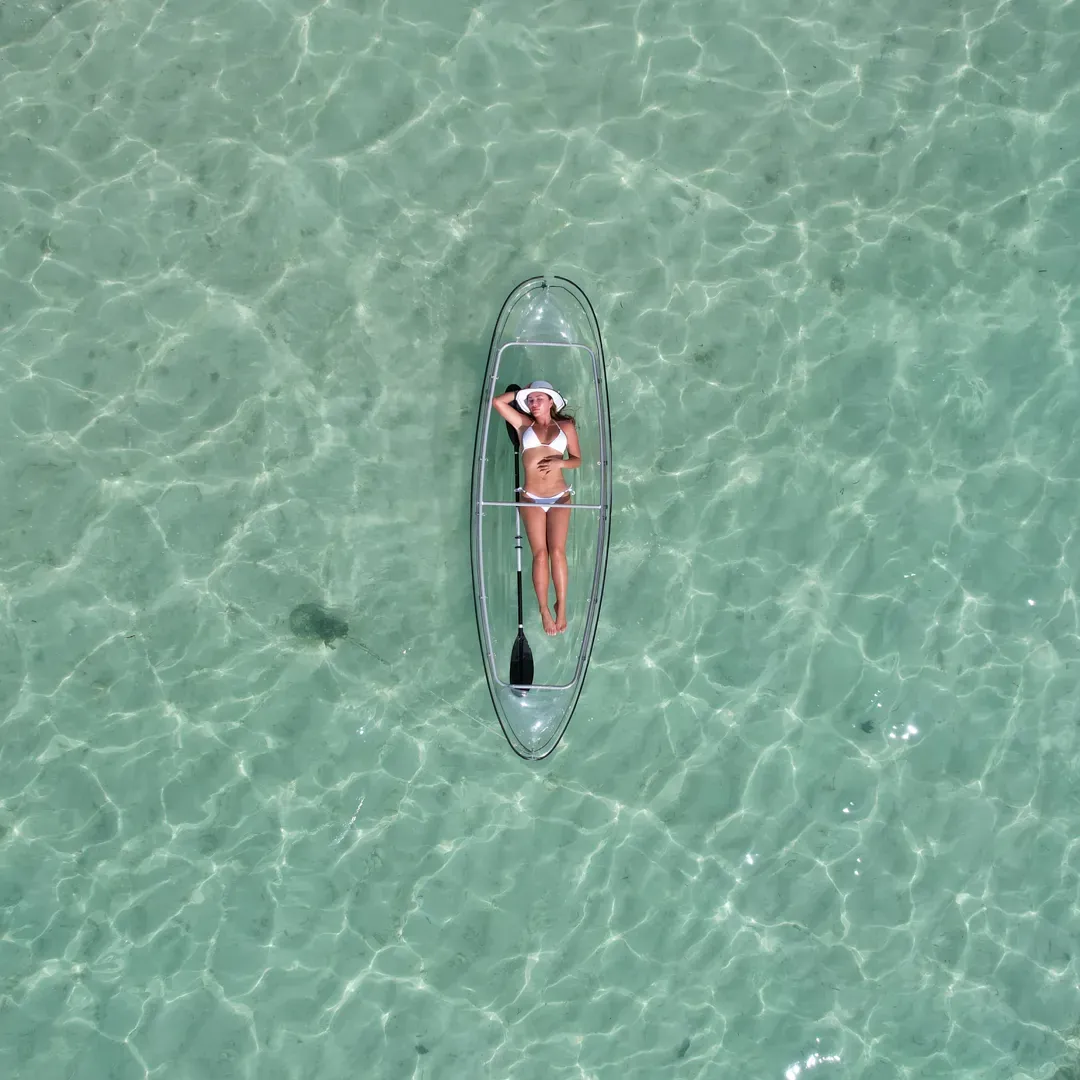 A single transparent kayak seen straight down through clear turquoise water
