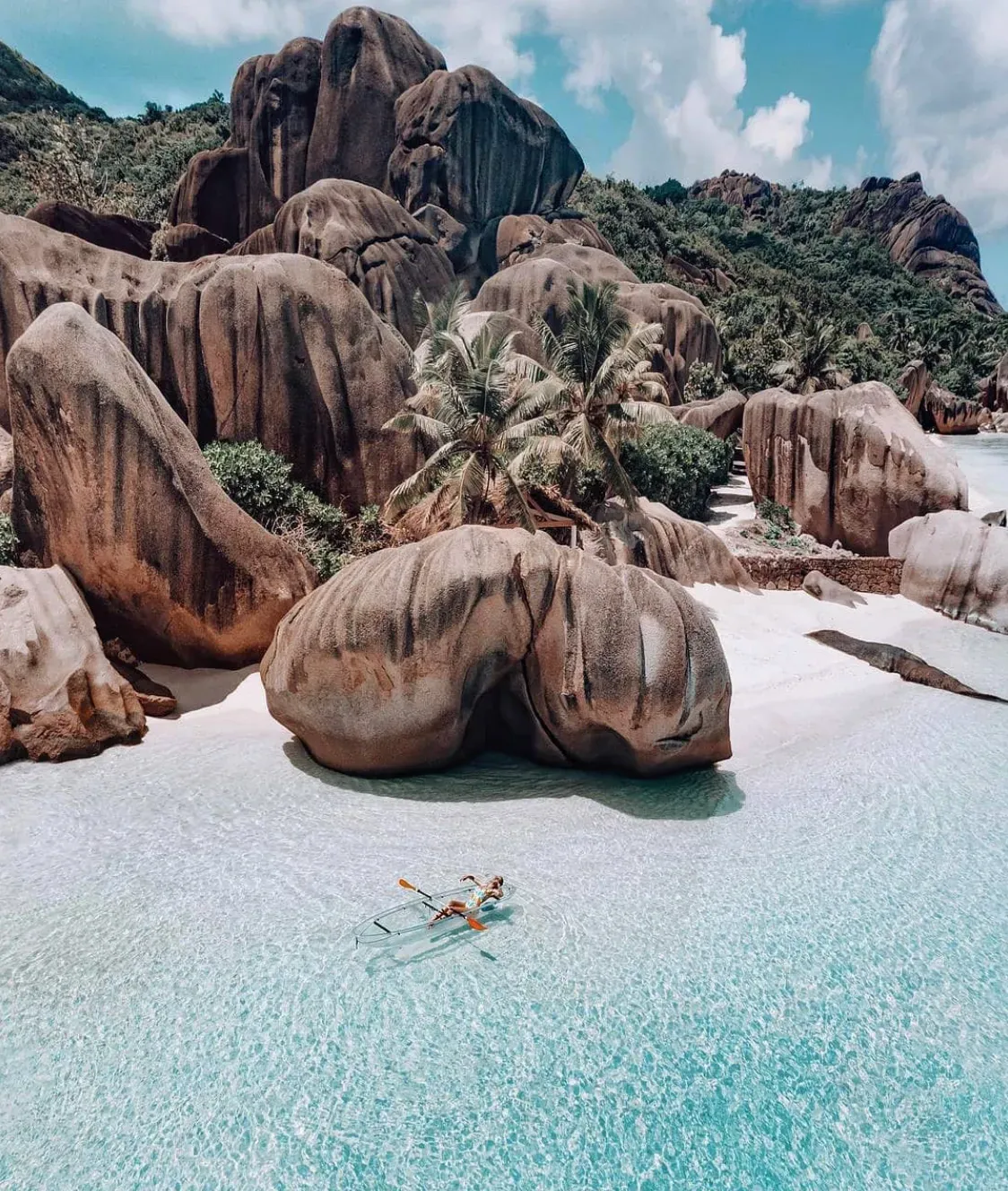 Aerial view of huge granite boulders, white sand and a clear kayak in the shallows
