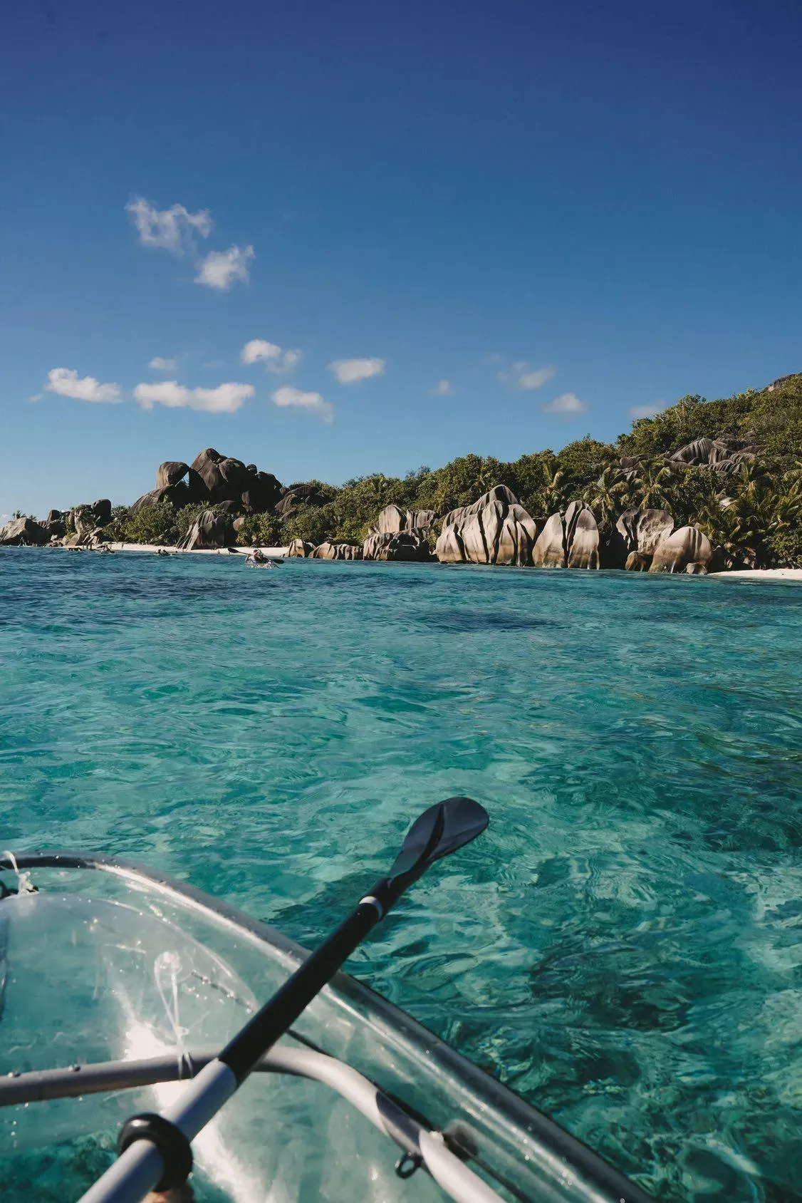 View forward over the bow of a transparent kayak across clear water