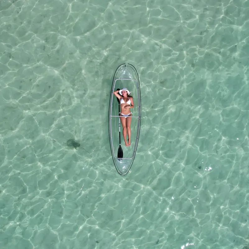 A single transparent kayak seen straight down through clear turquoise water