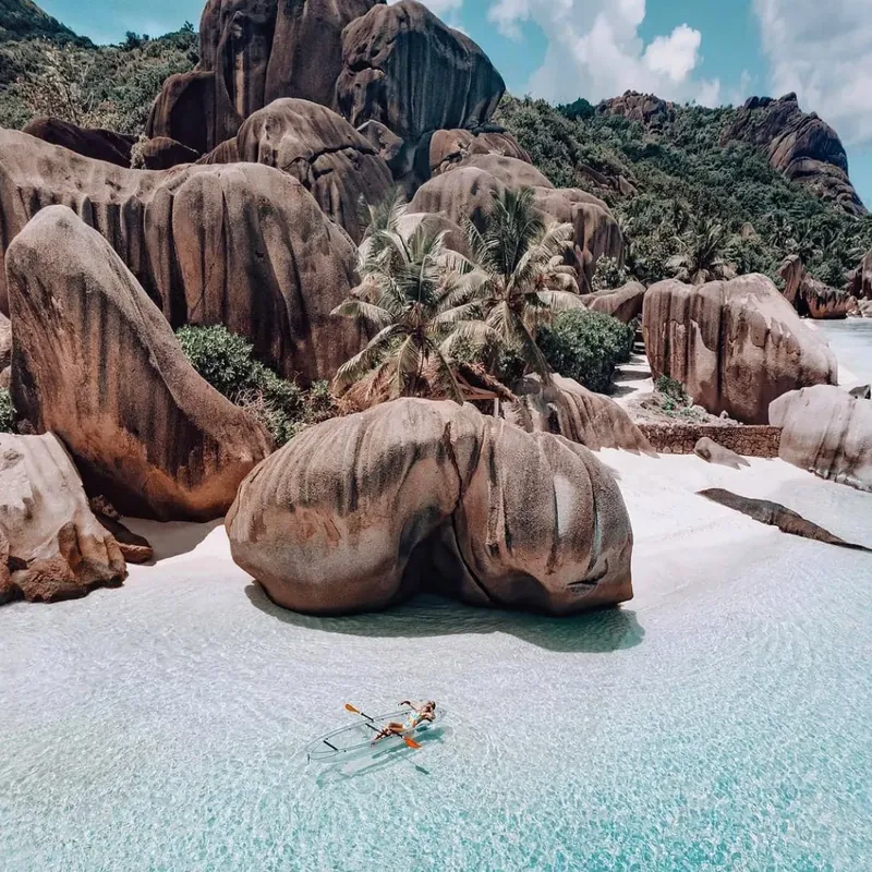 Aerial view of huge granite boulders, white sand and a clear kayak in the shallows