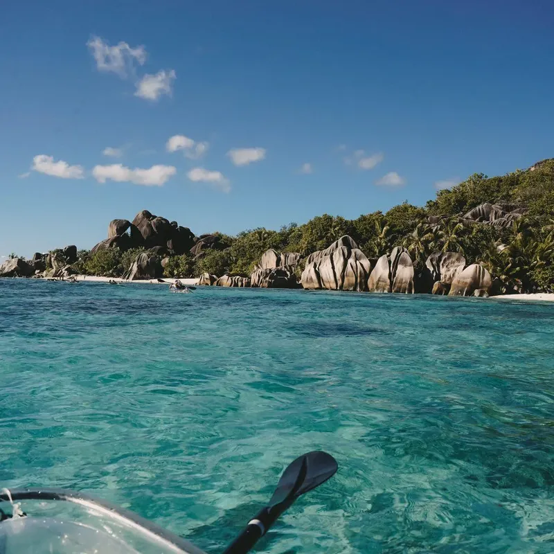 View forward over the bow of a transparent kayak across clear water